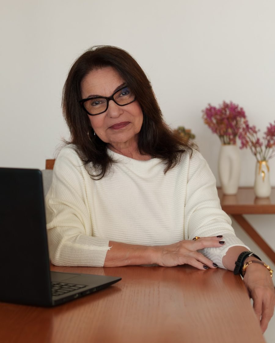 Elsa Saldanha sentada à mesa de trabalho, ao lado de um notebook, durante um atendimento