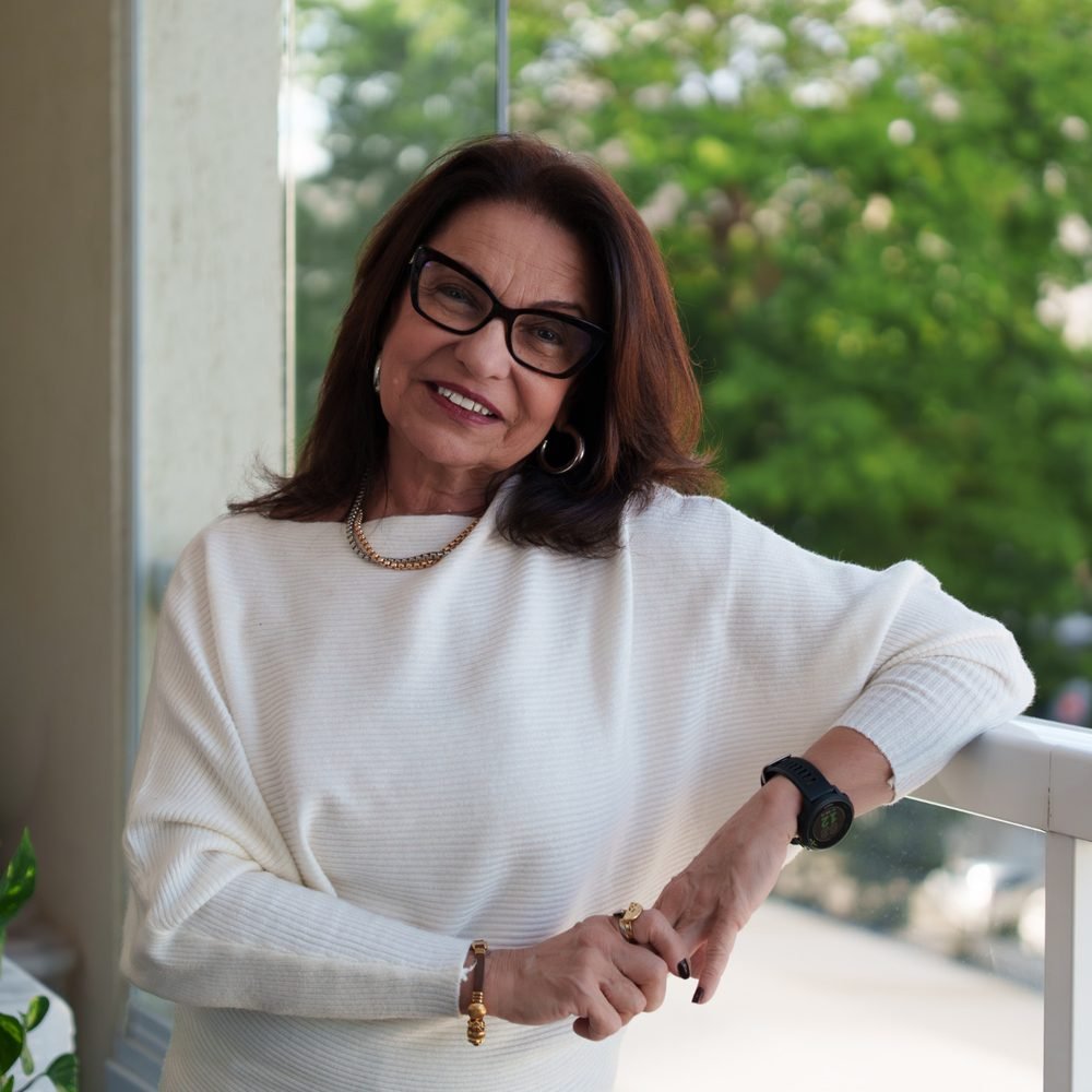 Elsa Saldanha, psicóloga clínica, apoiada na sacada do consultório, sorrindo para a câmera
